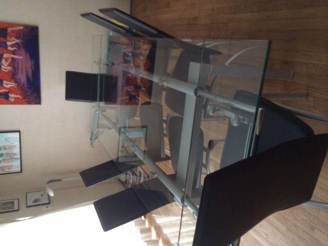Glass table on tripod with two black chairs
