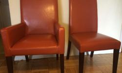 Beautiful and comfortable set of four leather dining chairs from Crate and Barrel in Persimmon color (a deep orange). Two of them have arm rests, two without. All four are in excellent condition with normal wear and tear along the legs. They are extremely