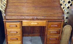 This is an undated antique Roll Top Oak Desk. This has had some repair and touch-up performed to it and has a rustic used look. One of the two pull out wings is missing it's wood edge and the front lock on the roll top has some scars. Storage caddy is in