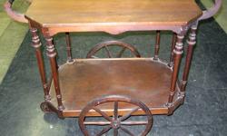 This an undated antique Tea Cart in good condition. The small pivot caster wheel is missing it's rubber tire and requires attention. The finish is less than perfect but this is still presentable and could use some touch-up or finish restoration. This has
