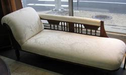 This an antique Chaise Lounge from the Victorian era in the Eastlake Style. It has been previously professionally restored including refinishing of the ornate wood frame with carved details and reupholstered with a quality white patterned fabric. This is
