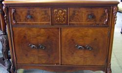This an undated antique Bar or Small Server Cabinet with beautiful Floral Marquetry Inlay details and bookmarked Veneer door faces. It appears to be constructed with Yellow Mahogany and has lovely grain patterns. Carved top back-splash as well as carved