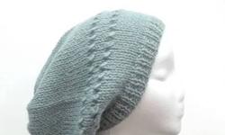 A beautiful soft blue hand knitted slouch hat that is made with an acrylic and wool blend yarn. 80% acrylic, 20%wool. Very stretchy, will fit any head, stretches out to 31 inches around. It has two rows of eyelets. The measurements are lying flat on a