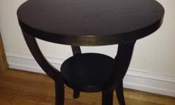 Round, wood coffee/ side table in BROWN from West Elm. Purchased only 8 months ago.
Description from the website:
Our Silhouette Nightstand is a contemporary reinterpretation of the classic pedestal table. With a lower shelf for extra storage and display,