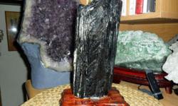 Exceptional and Beautiful Huge Black Tourmaline Crystal Specimen Healing on a Beautiful Brown Wooden Base. Black Tourmaline, also known as schorl, is associated with the root or base chakra, and is excellent for grounding excess energy. It is a well known