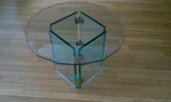 16.5 inches high
27 inches wide
Clear glass. Base is made of four 16 (tall) by 10 inch (wide) glass panels; 1 inch thick held together by 4 nickle clasps.
Table top is clear glass 1 inch thick, not round but rather a geometrical shape with more than 15
