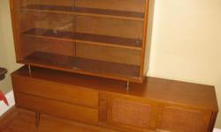 Here's an original mid-century wall unit/credenza/cabinet. Circa 1960s. It features a display area with for your glassware or collectibles, as well as drawers and a cabinet for storage. The shelves adjust. Its probably made of walnut or teak. In very