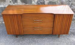 Storage meets style here. This fabulous case piece features quality construction throughout and a great design. Its subtle lines and tapered legs screams mid-century modern. Features 3 center drawers and 2 side cabinets. It can be used as a server,