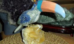 This handmade Toucan has been carved from Natural Gemstone Rocks. This beautiful Toucan stands on a Calcite Crystal Quartz perch. The body was carved from Sodalite with Chrysocolla in crustations. The beak was carved from Celestine, Blue, and Orange