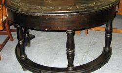 This is a unique vintage stained circular desk with carved top and turned legs. It features one curved center draw. This piece shows it's age with some wear spots to the finish as well as a few dents, scratches, and marks on the top as well as some mars