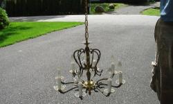 This is a lovely ornamental brass and Crystal Chandelier. The chandelier features eight scrolled arms. At the ends and around the bottom of the bulbs are beautiful crystals that hang down. Total of 64 crystals.The center features a embossed column