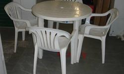 White plastic outdoor table with central hole for an umbrella. The four legs disassemble and store inside table. Includes four comfortable white plastic chairs that are stackable taking up very little room when not being used. Make me an offer.