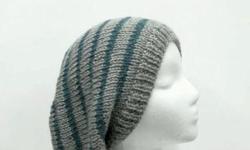 A hand knitted slouch hat oversized beanie is a medium silver gray with stripes of turquoise that has a metallic thread knitted into the stripes(see close up). This slouch hat is made with an acrylic yarn. Medium thickness, very stretchy, will fit any